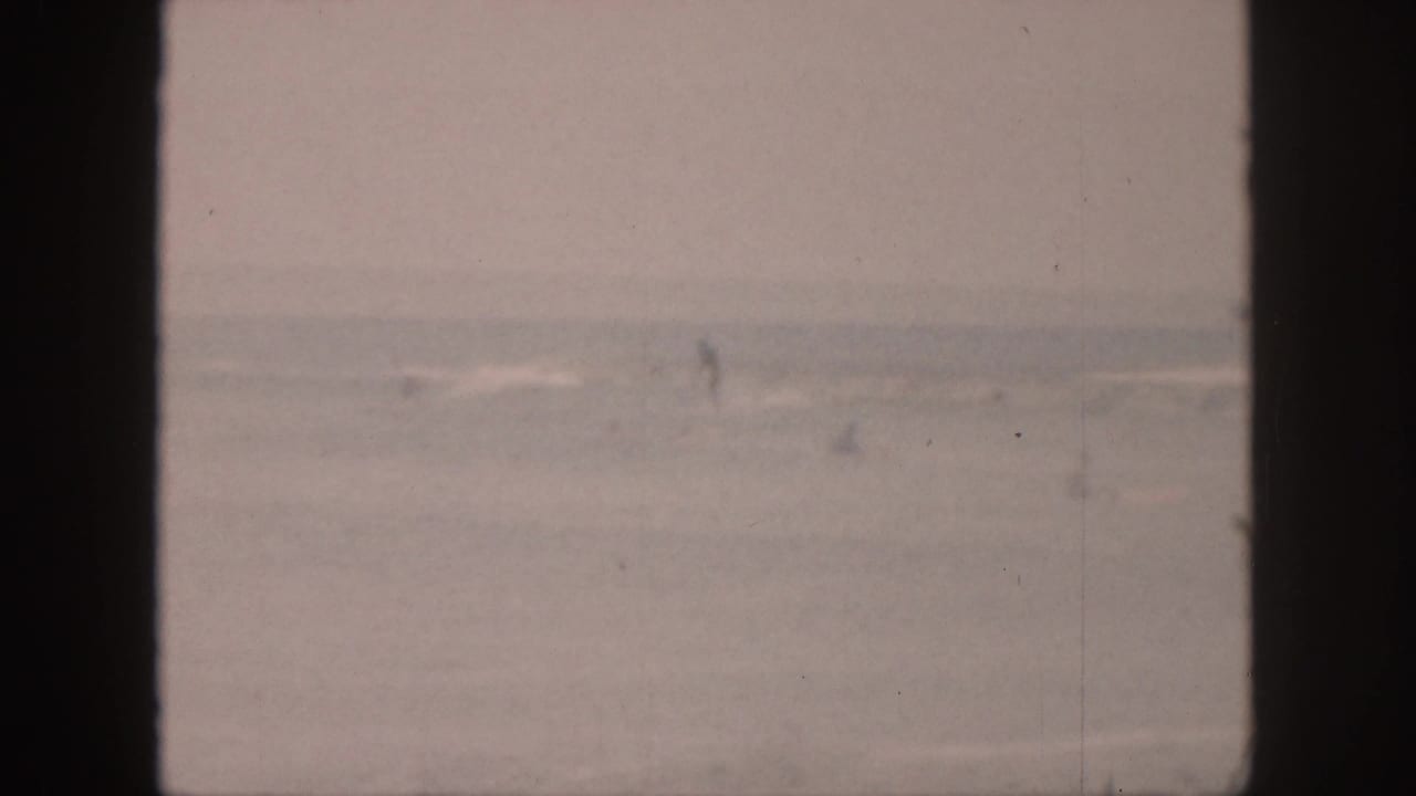 A faded 1959 Hawaii ocean view shows distant white surf and pale water behind dark window mullions.