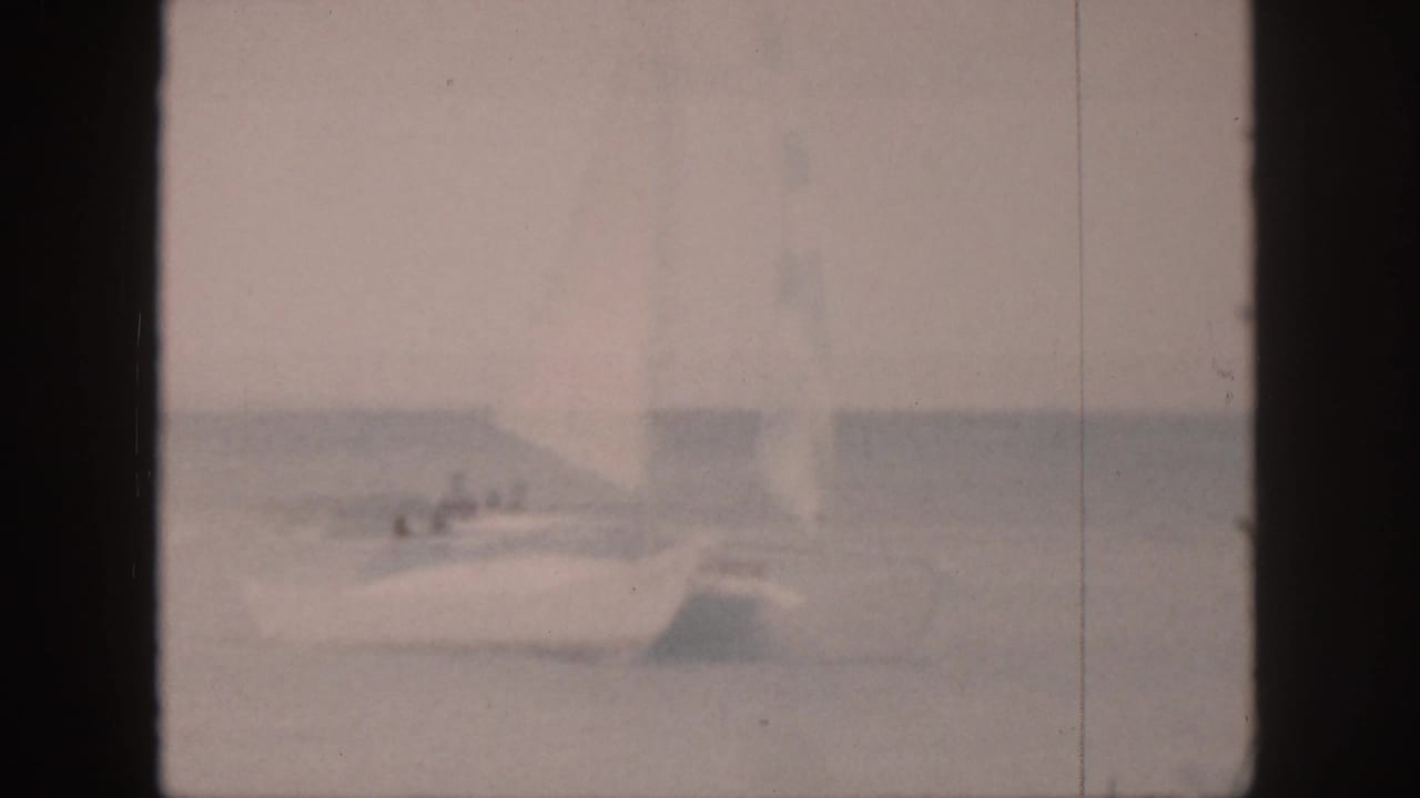 White sailboat under a pale sail seen through soft focus.