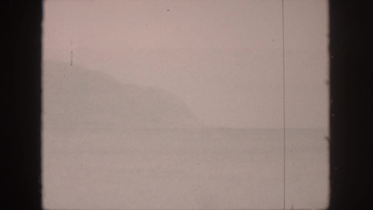 Soft hazy landscape with distant ridge shapes and a central dark film border.