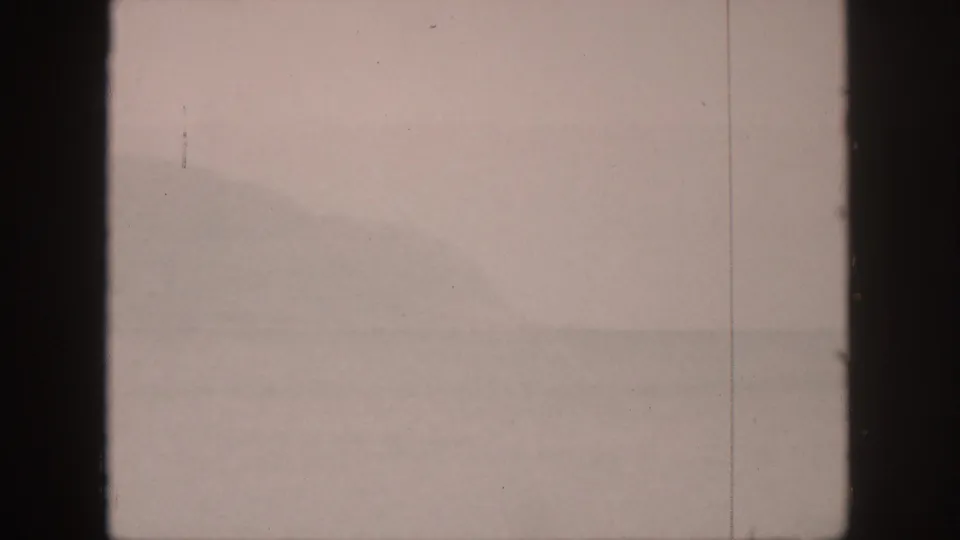 1959 Hawaii home-movie frame showing a pale misted landscape, distant ridge forms, and a prominent vertical film edge.
