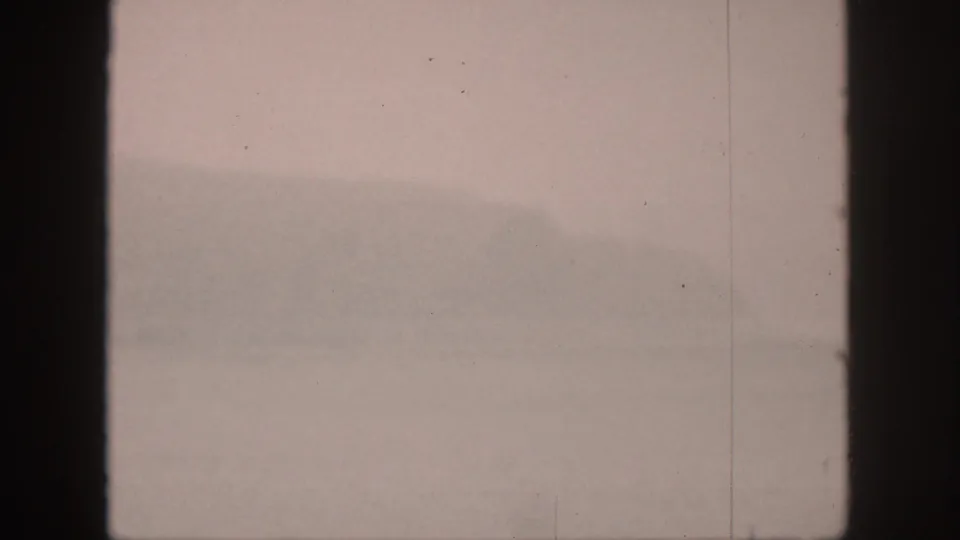 1959 Hawaii home-movie frame showing pale mist over water, a faint indistinct shape, and dark 8mm frame edges.