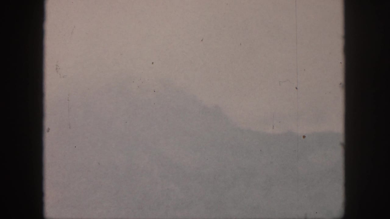 Distant mountain slope blurred by haze behind a dark central window frame.
