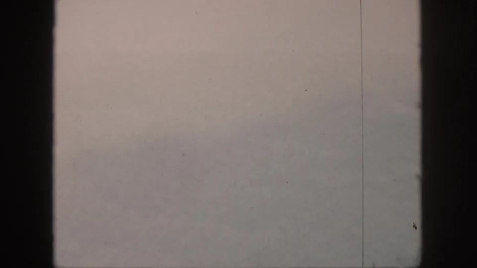 1959 Hawaii archival frame showing a pale foggy landscape with a faint mountain edge beside a dark vertical window frame.