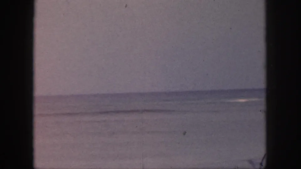 Faded 1959 Hawaii coastal view with small surf breaks on the horizon, framed by dark vertical window or doorway edges.