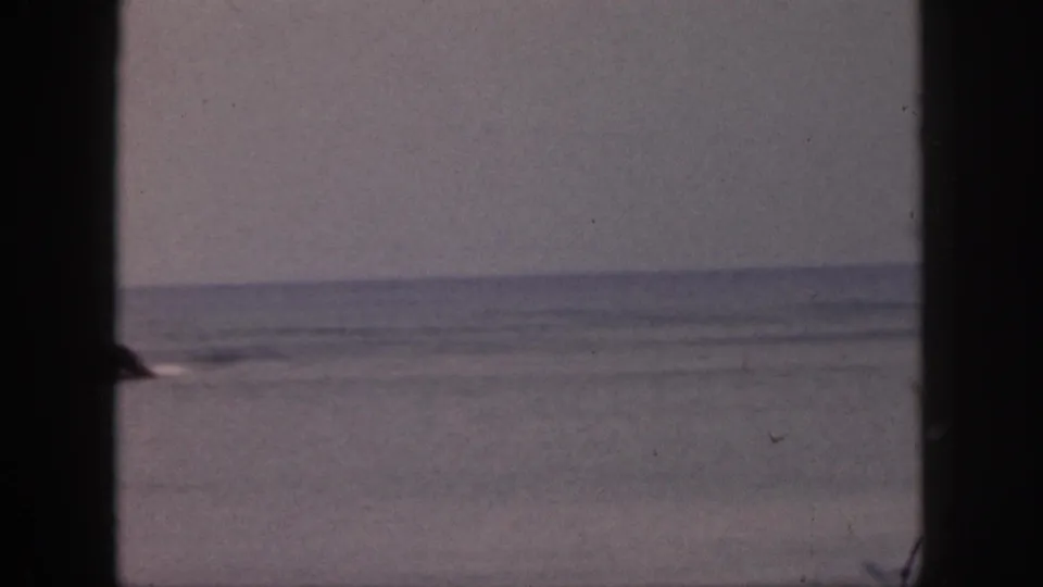 1959 Hawaii ocean view with a small dark rocky outcrop or island shape near the horizon, seen through a dark frame.