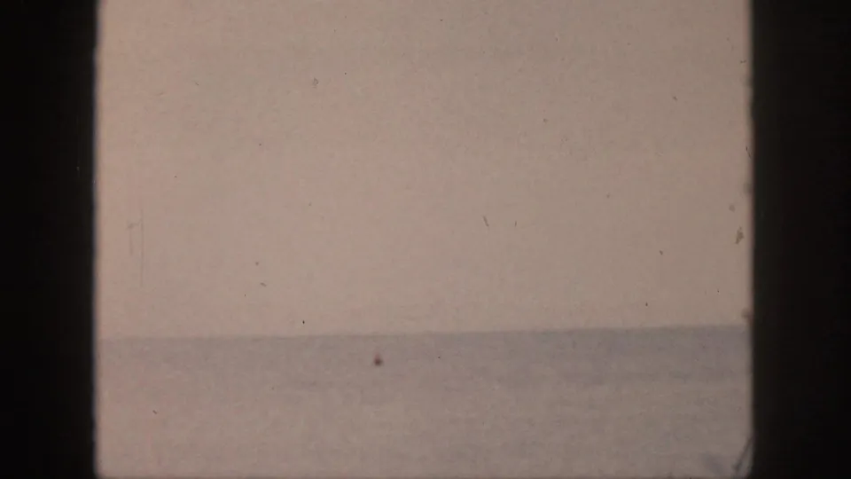 1959 Hawaii shoreline view with pale sky, muted ocean horizon, and dark film or window-frame edges visible in the composition.