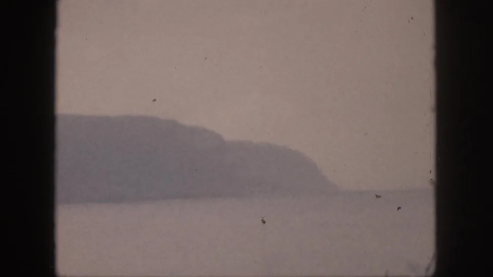 1959 Hawaii 8mm frame with a hazy mountain or headland across water, softened by age, grain, and exposure.