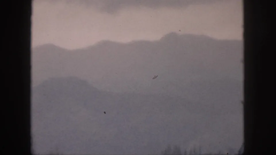 1959 Hawaii 8mm view of misty mountain layers, faint trees, and window framing across the scene.