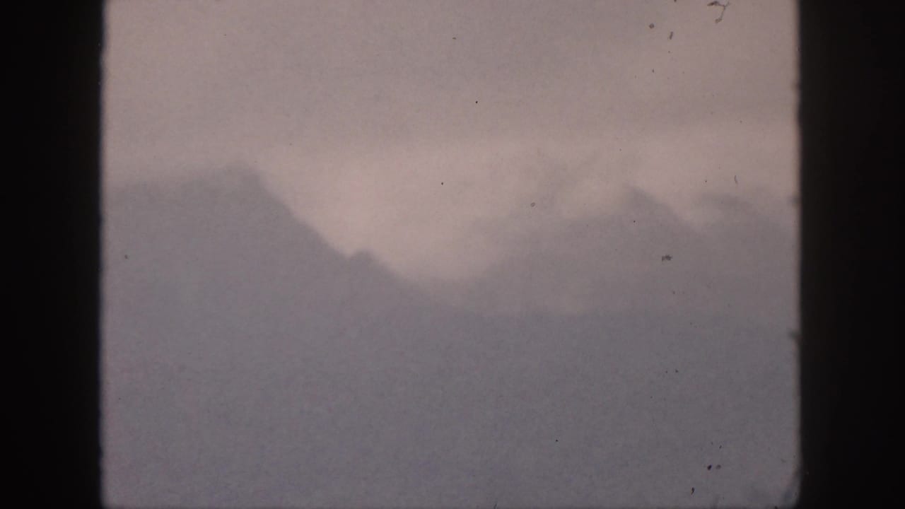 1959 Hawaii 8mm frame showing distant mountain peaks softened by haze beneath a muted sky.