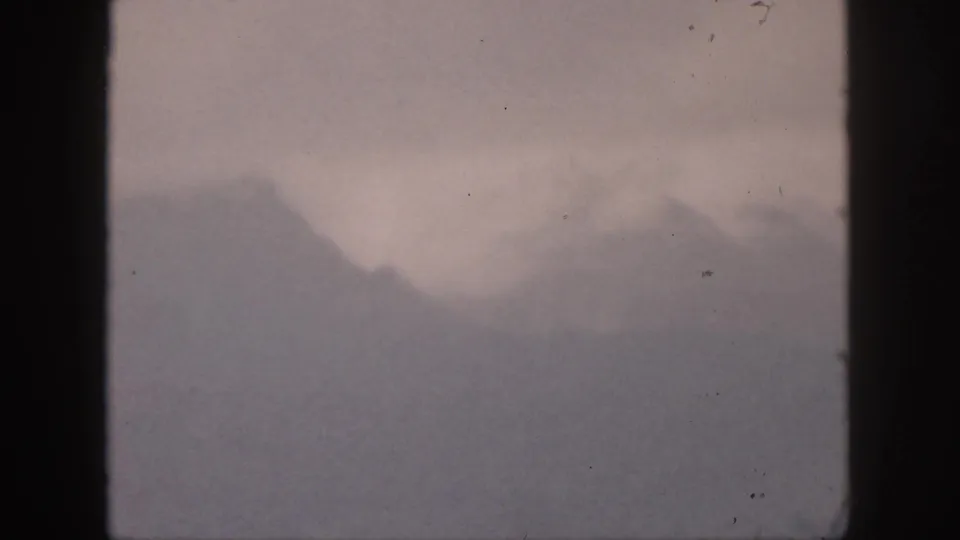 1959 Hawaii 8mm frame showing distant mountain peaks softened by haze beneath a muted sky.