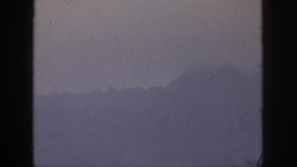 1959 Hawaii home-movie frame with low-contrast mountain silhouettes fading into fog or haze.