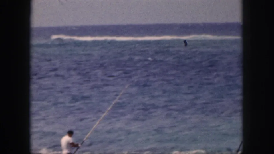 1959 Hawaii frame with a distant adult fisherman near the lower edge of the frame and open ocean beyond.