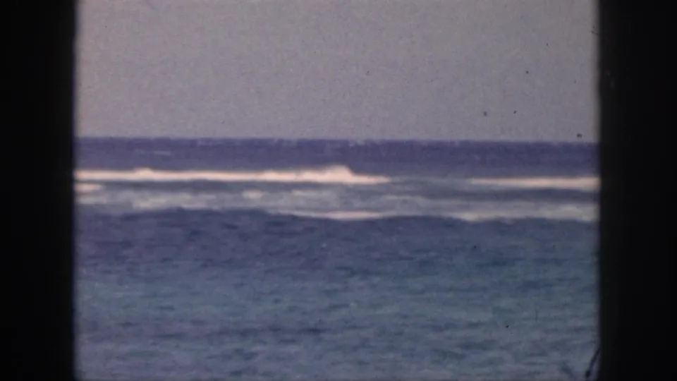 1959 Hawaii 8mm frame showing blue ocean surf and white wave lines viewed through a dark window or doorway frame.