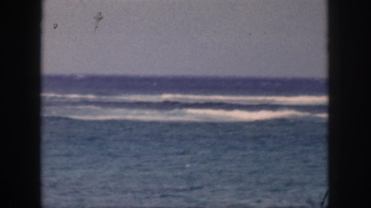 Blue-green sea with breaking white surf framed by dark edges.