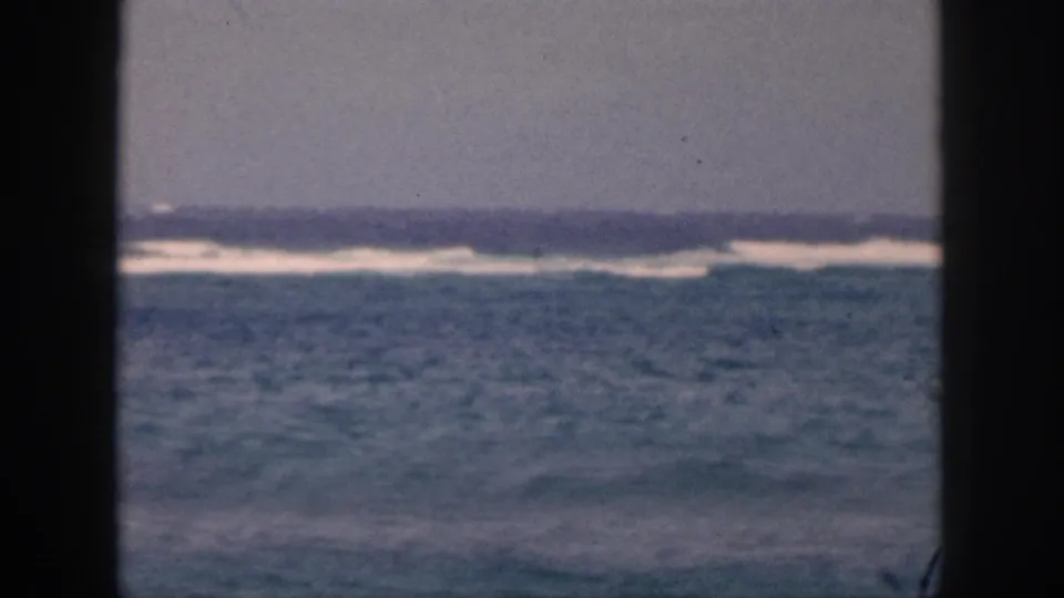 1959 Hawaii 8mm frame showing a low, soft-focus ocean view with distant waves and muted sky through a framed opening.