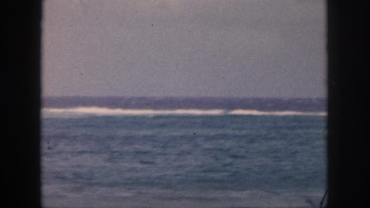 1959 Hawaii 8mm view of blue-green ocean water and distant white surf through a dark window or doorway frame.