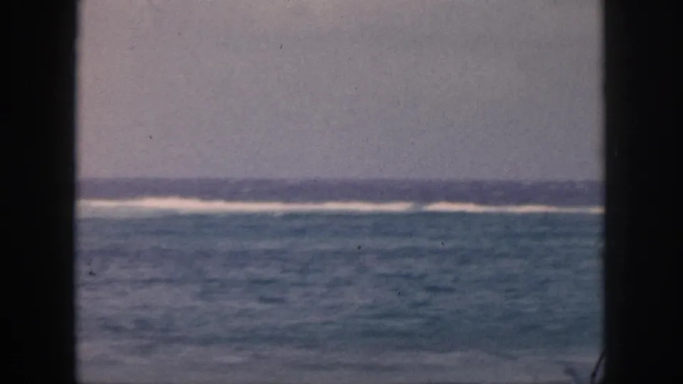1959 Hawaii 8mm view of blue-green ocean water and distant white surf through a dark window or doorway frame.