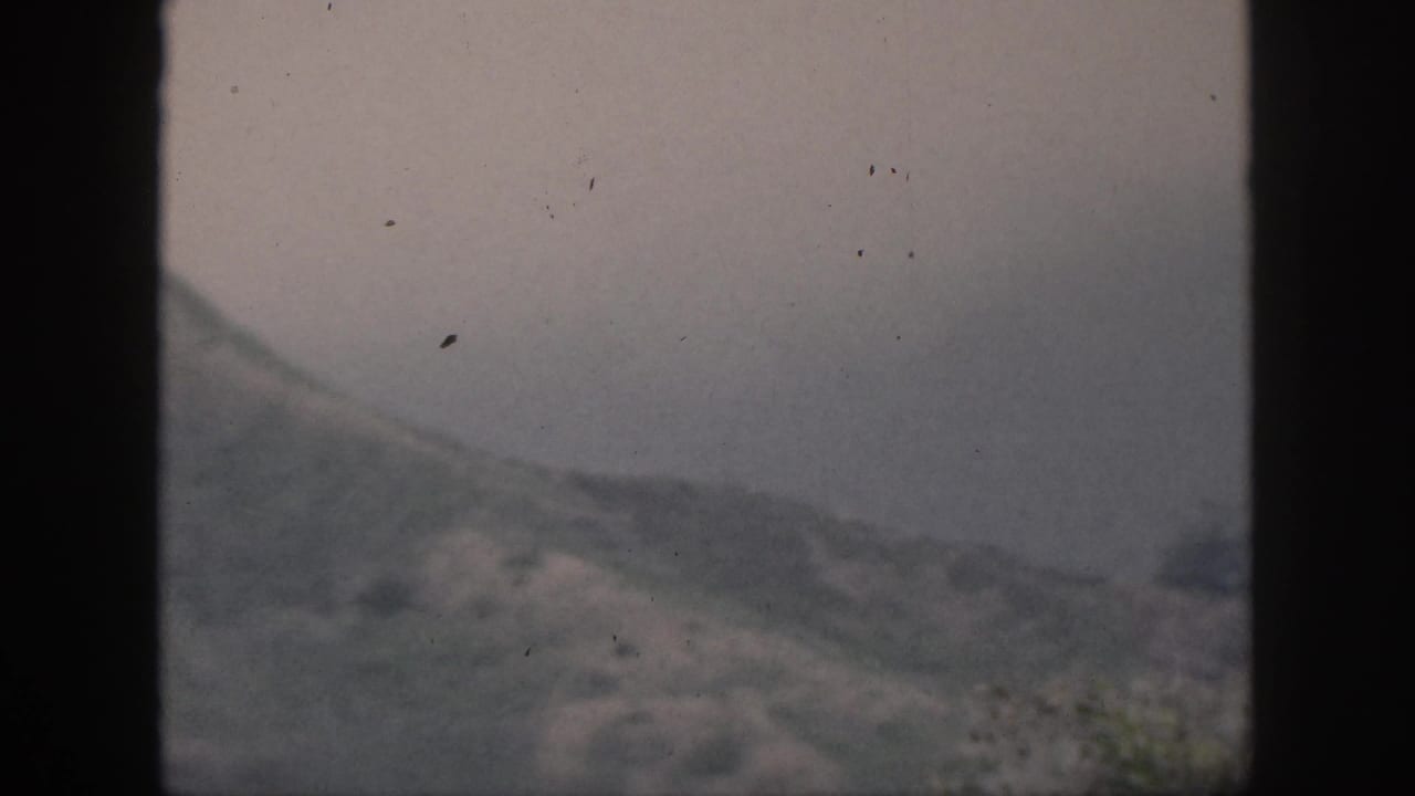 Soft mountain slope and pale sky divided by window mullions.