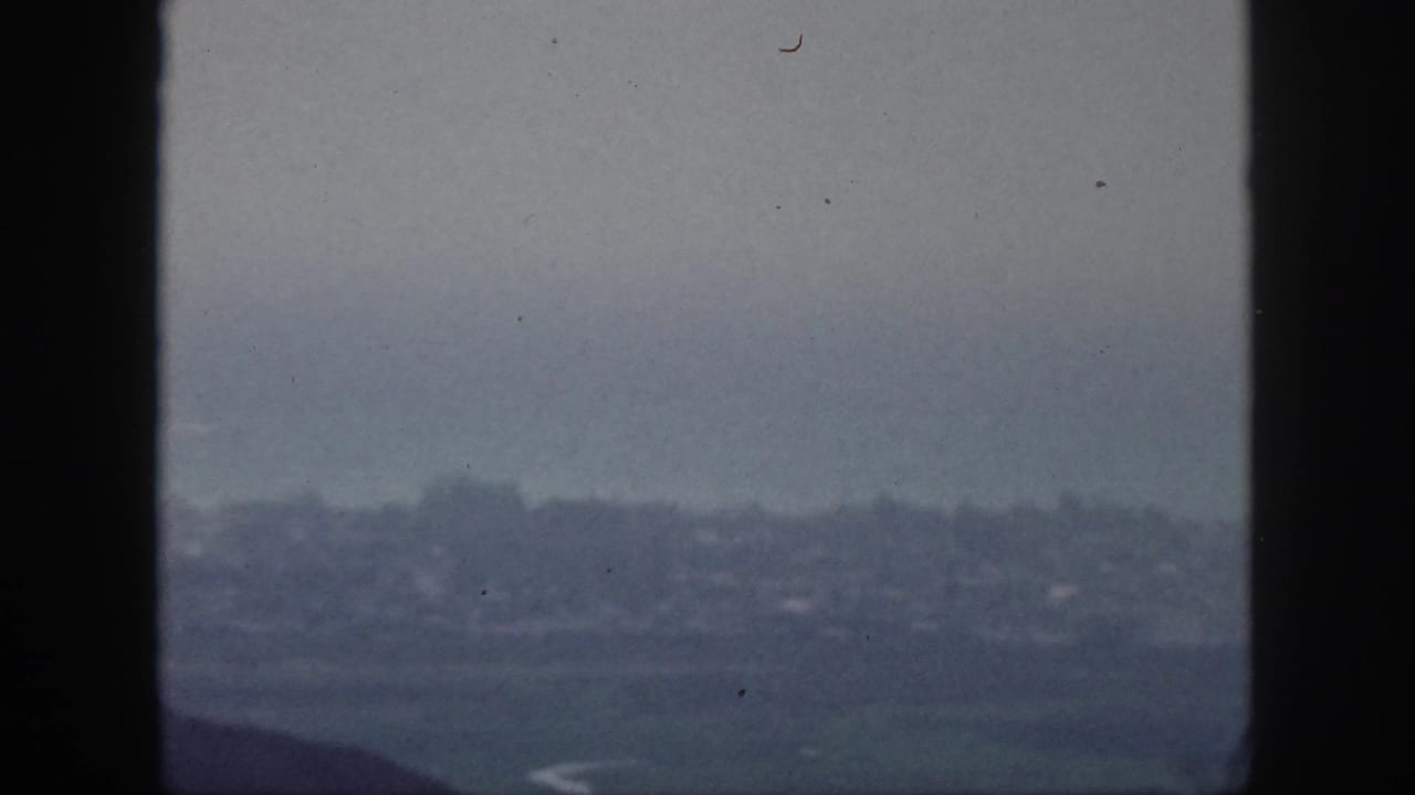 1959 Hawaii 8mm frame showing a soft, hazy distant city or shoreline view through a vertical window frame.