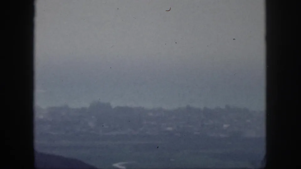 1959 Hawaii 8mm frame showing a soft, hazy distant city or shoreline view through a vertical window frame.