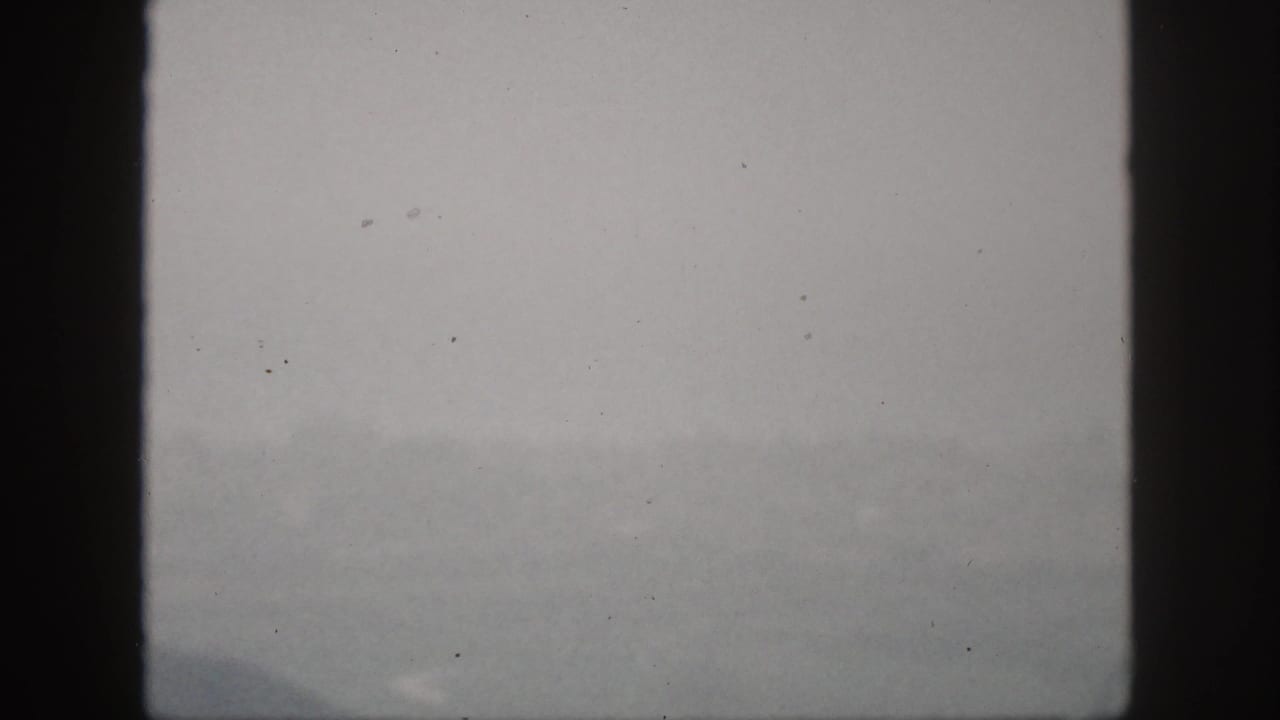A very faint 1959 Hawaii view through window framing shows haze over water and indistinct land or city forms.