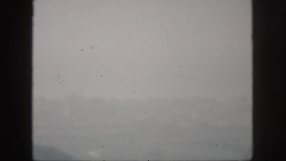 A very faint 1959 Hawaii view through window framing shows haze over water and indistinct land or city forms.