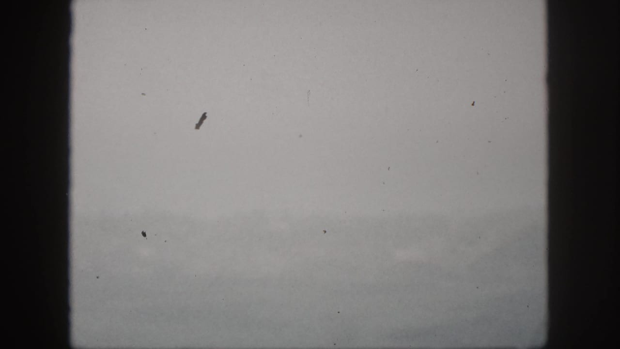 A soft 8mm view of mist and faint hills in Hawaii, framed by a dark central window divider.