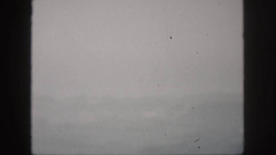 1959 Hawaii 8mm frame with muted gray fog, distant hillside shapes, and dark window framing.
