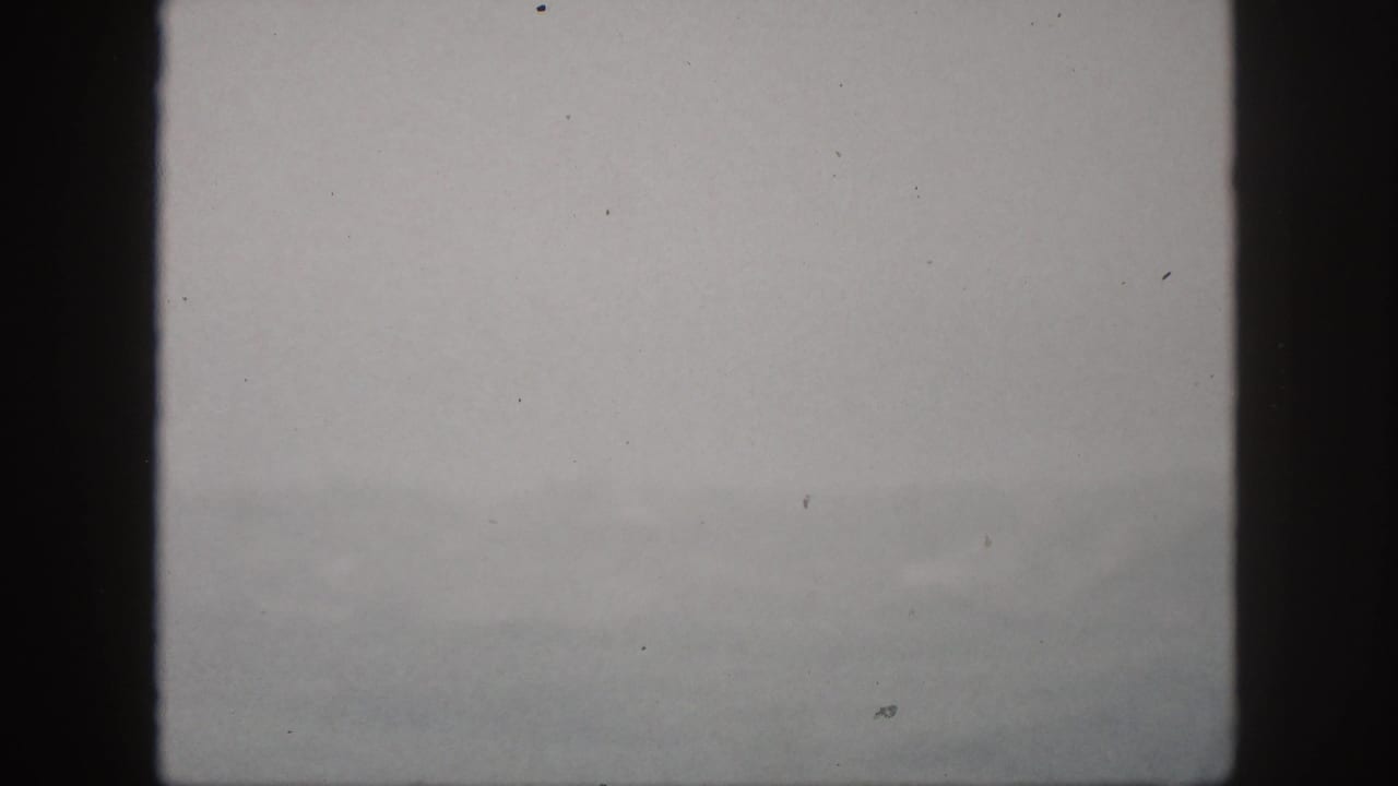Hawaii home-movie still from 1959 showing a dim, foggy landscape beyond dark window framing.