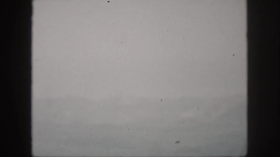 Hawaii home-movie still from 1959 showing a dim, foggy landscape beyond dark window framing.