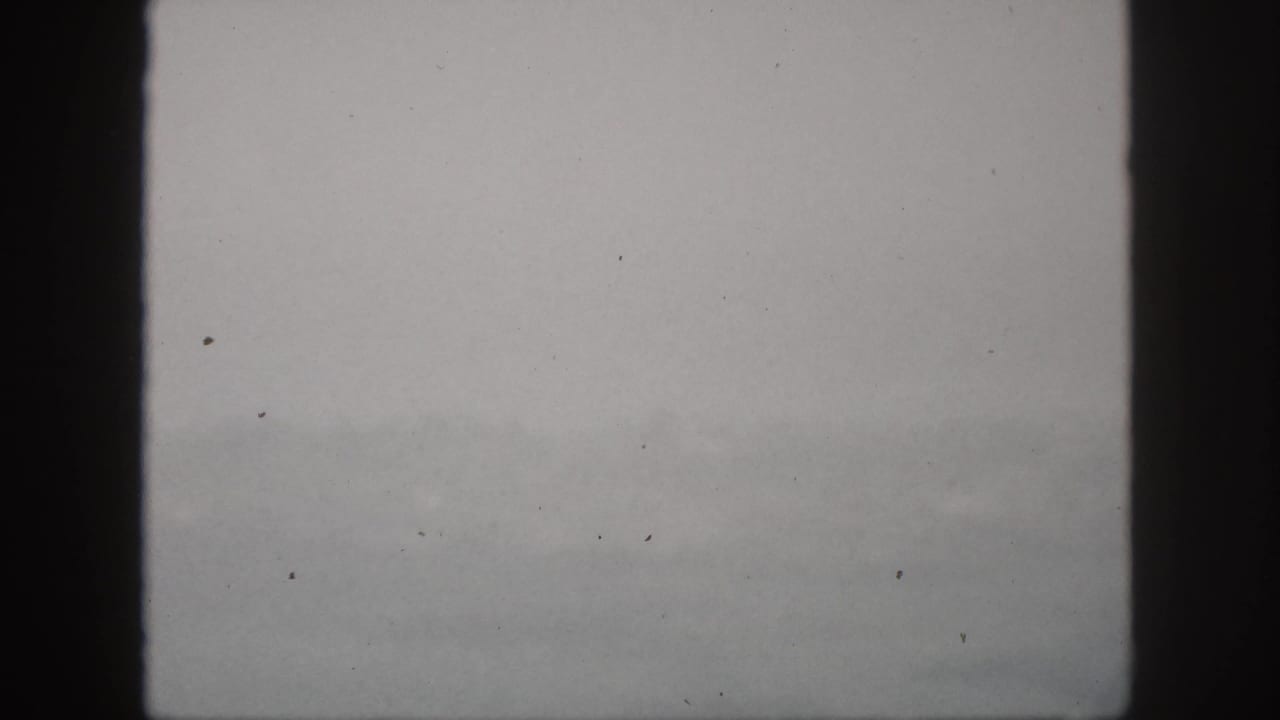 1959 Hawaii 8mm frame showing hazy hills and mist through a dark vertical window frame.
