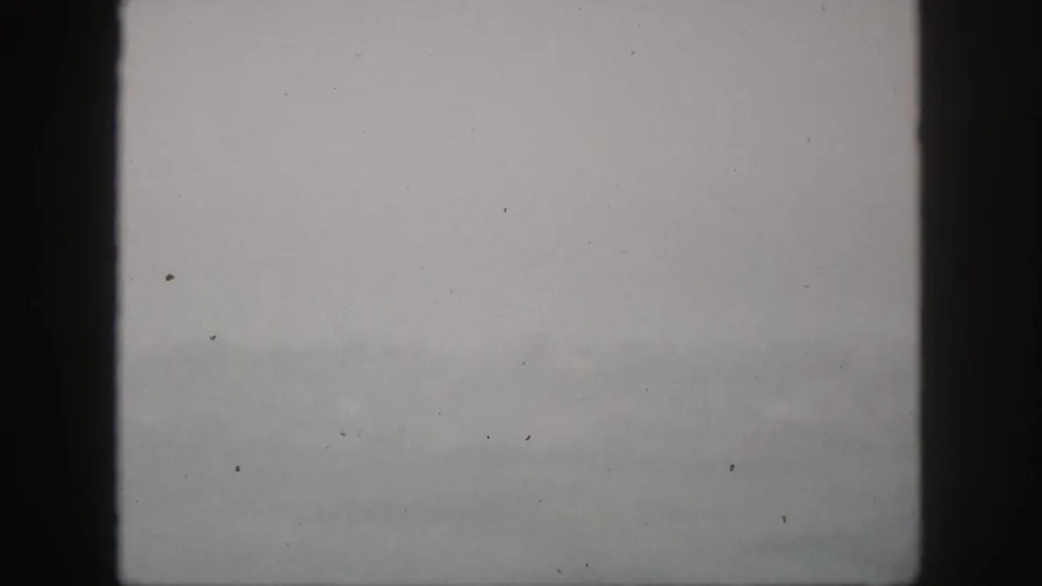 1959 Hawaii 8mm frame showing hazy hills and mist through a dark vertical window frame.