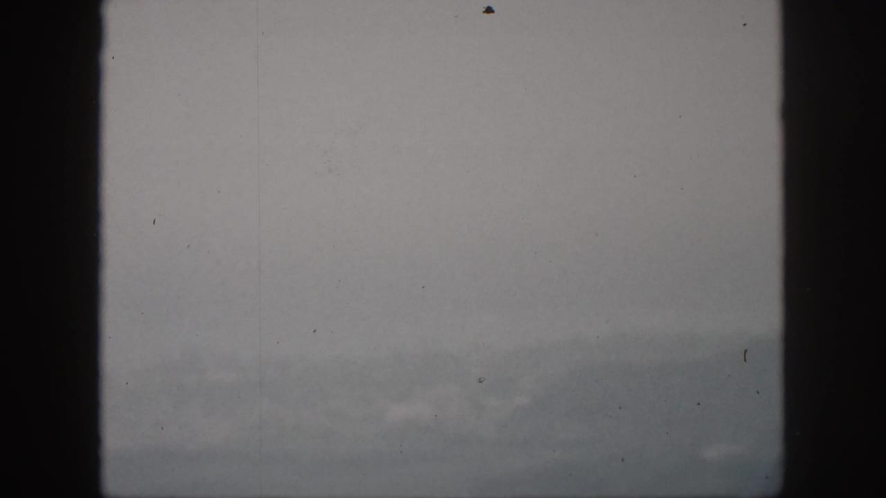 1959 Hawaii archival frame with a distant fog-softened mountain silhouette and dark vertical framing at the sides.