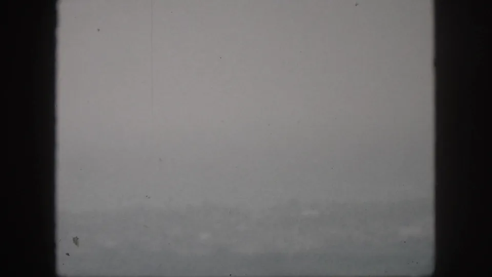 1959 Hawaii 8mm frame showing a pale foggy landscape with faint mountain forms and visible film dust.