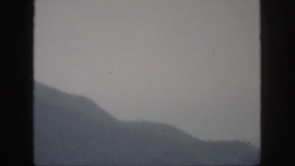 1959 Oahu 8mm frame showing layered misty hills and a low ridgeline under an overcast sky.