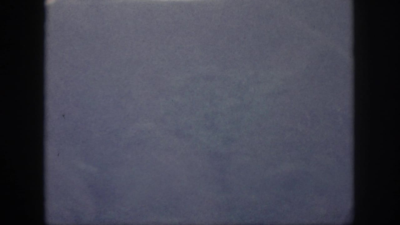 1959 Oahu frame with faint mountain surface texture and blue-gray haze, framed by dark 8mm scan borders.