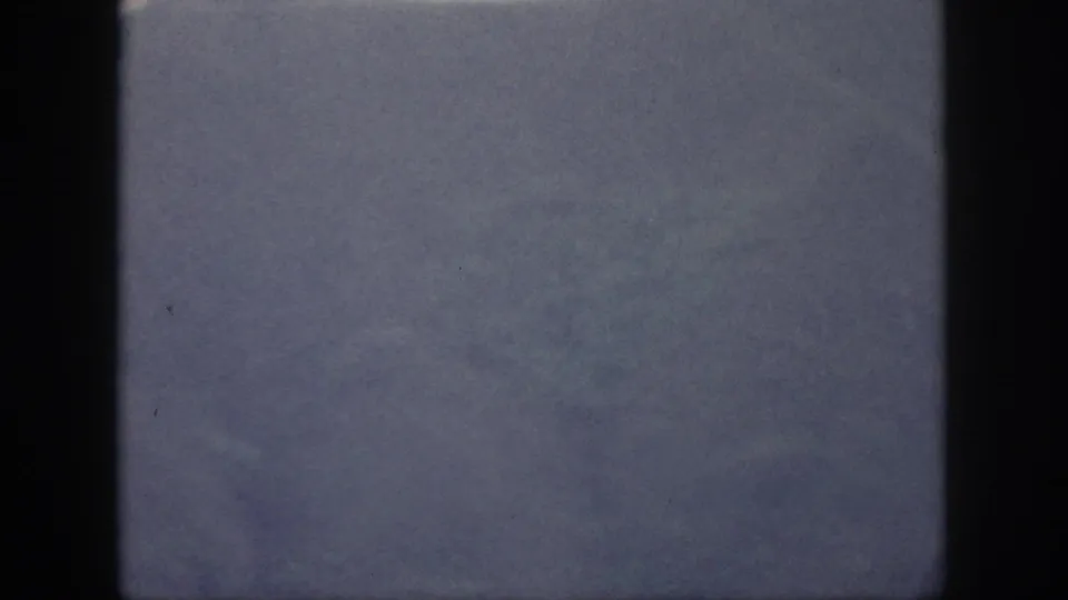 1959 Oahu frame with faint mountain surface texture and blue-gray haze, framed by dark 8mm scan borders.