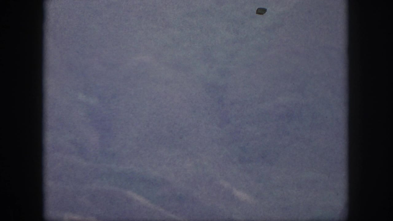 Hazy Oahu mountain ridges from 1959 8mm home-movie footage, with muted color and dark gate edges.