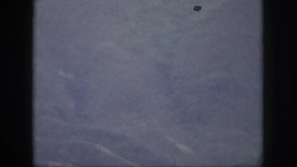 Hazy Oahu mountain ridges from 1959 8mm home-movie footage, with muted color and dark gate edges.
