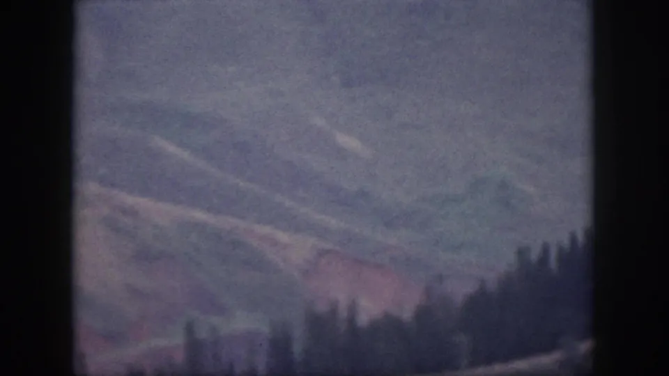 1959 Oahu mountain terrain with pale ridges, reddish soil tones, and a dark tree-lined crest.