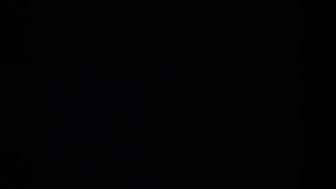 Near-blank dark section of the 1959 8mm clip, showing faint color noise and film texture rather than a visible scene.
