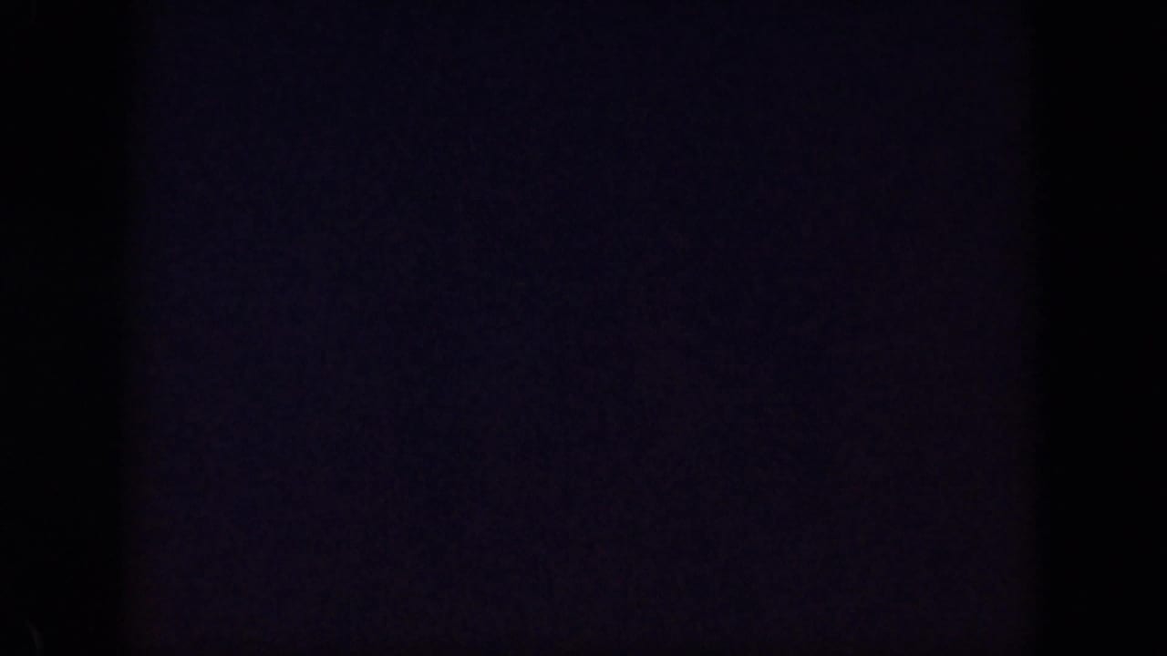 Near-blank ending frame from the 1959 Oahu 8mm footage, with dark exposure, faint purple tone, and visible film grain.