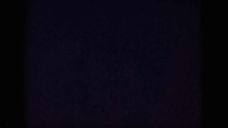Near-blank ending frame from the 1959 Oahu 8mm footage, with dark exposure, faint purple tone, and visible film grain.