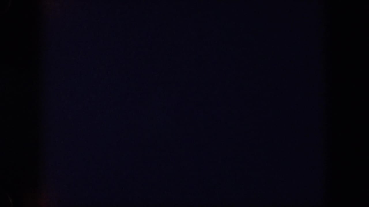 Underexposed 1959 Oahu 8mm frame with a dark window edge and a distant naval vessel across the harbor.
