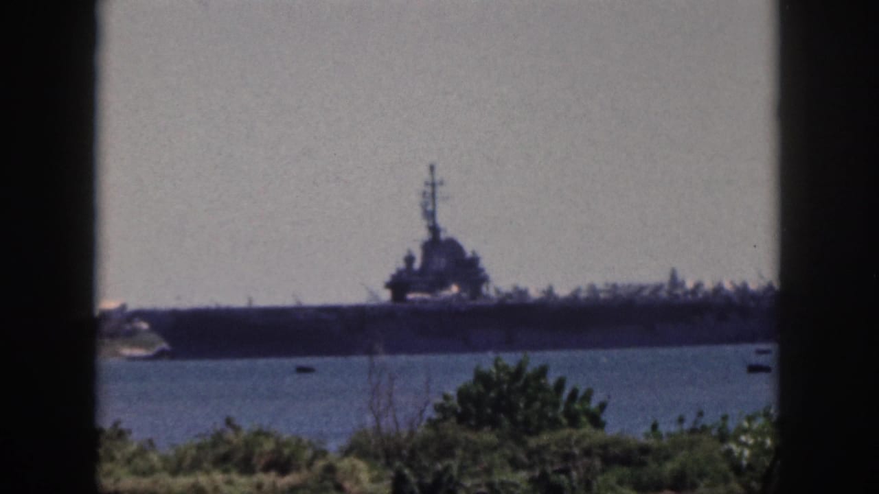 The 1959 Oahu harbor view continues, showing the naval ship, calm water, small boats, and green shoreline plants.