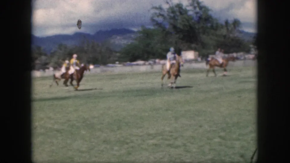 Polo players ride across an Oahu field in 1959, with the action framed from a distant spectator position.