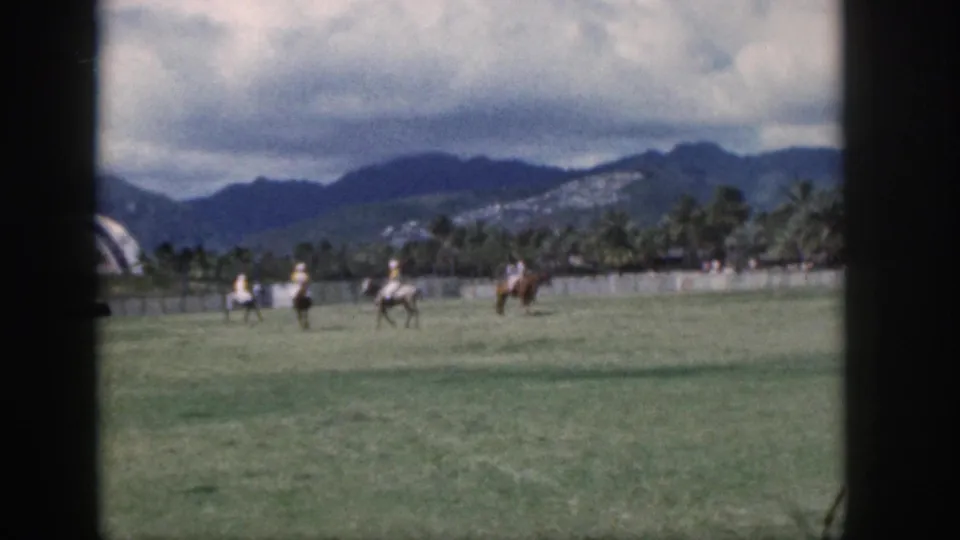 Oahu, Hawaii, 1959 frame of polo riders spaced across a grass field, filmed from a distant spectator viewpoint.