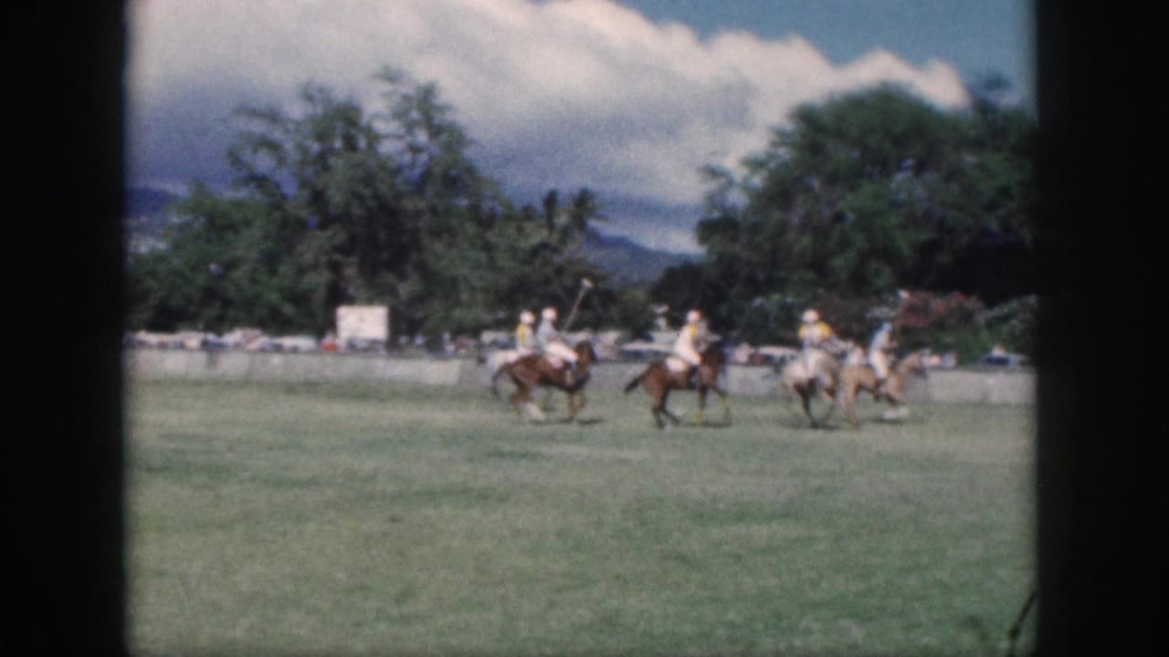 1959 Oahu polo match frame with several riders grouped in play, their mallets visible against the open grass field.