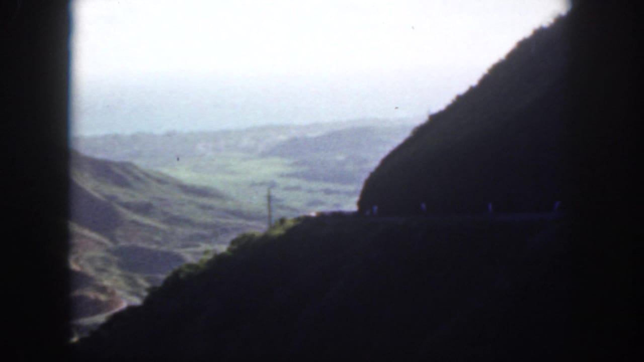 View from a dark tunnel opening toward pale sky and distant green hills.