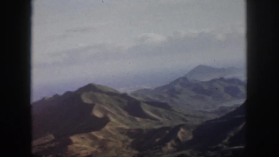 1959 Oahu 8mm frame with softened mountain ridges, valley forms, and a hazy horizon.